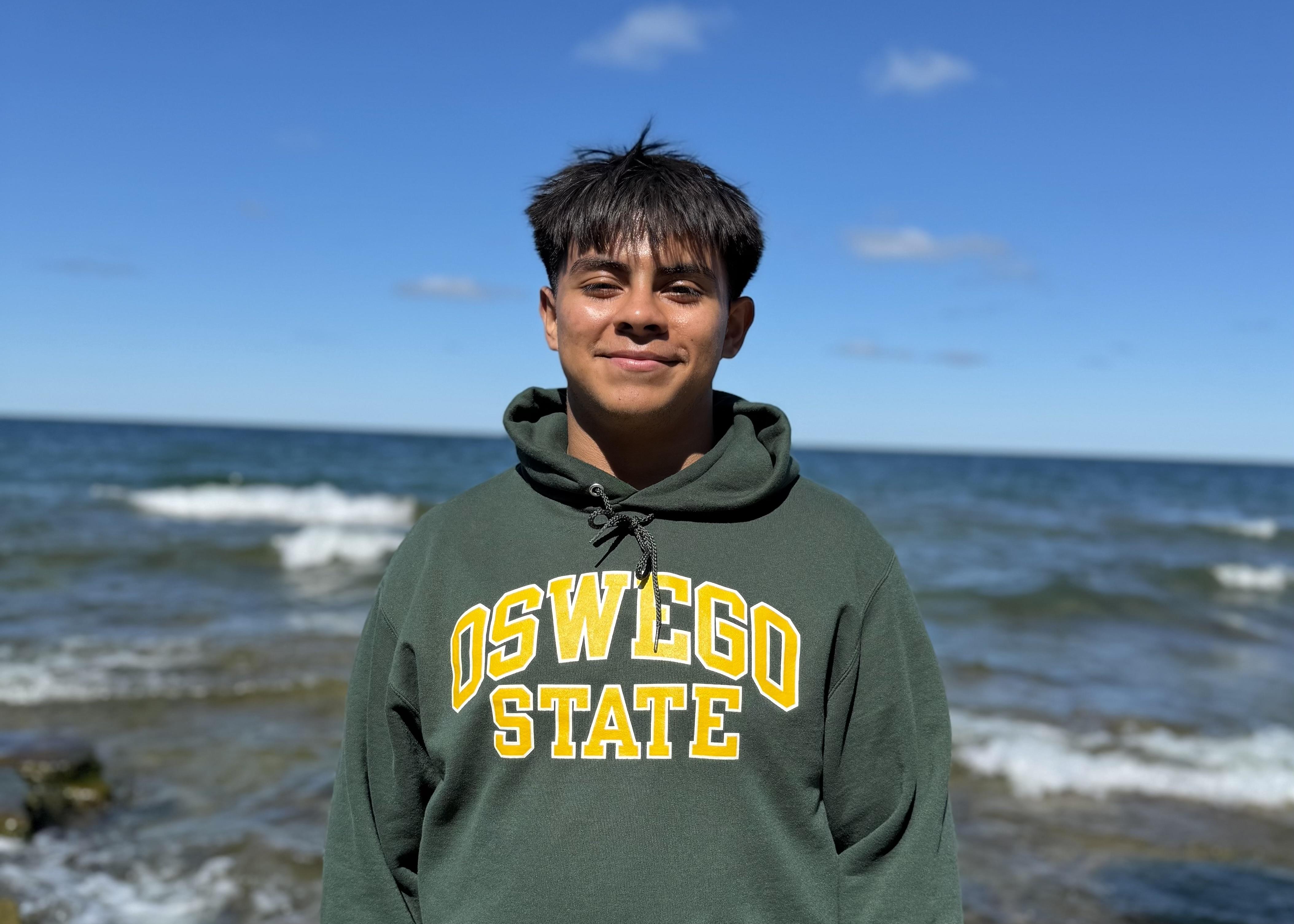 First-year SUNY Oswego student Axel Lopez smiling for a photo at Lake Ontario.