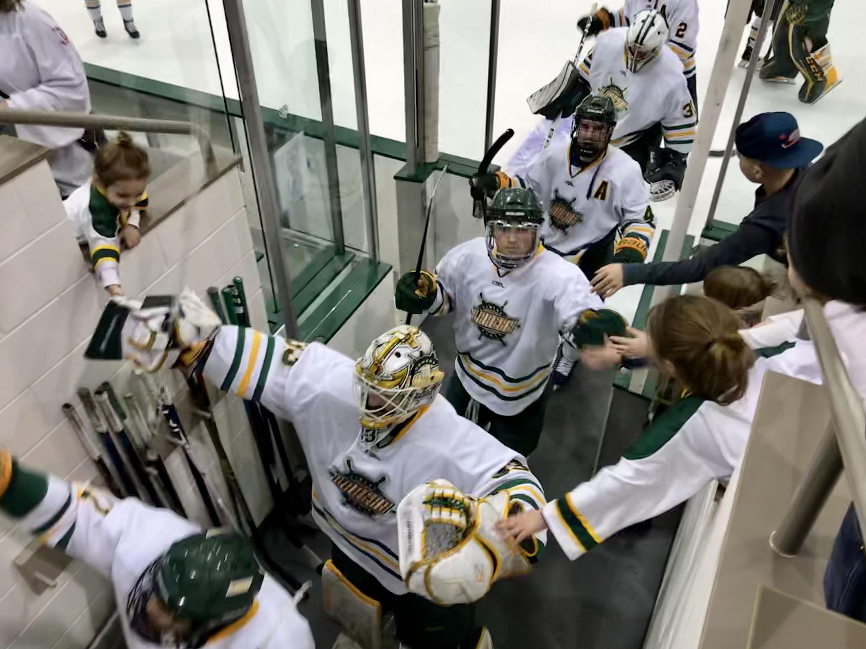 Men's hockey team high fives fans