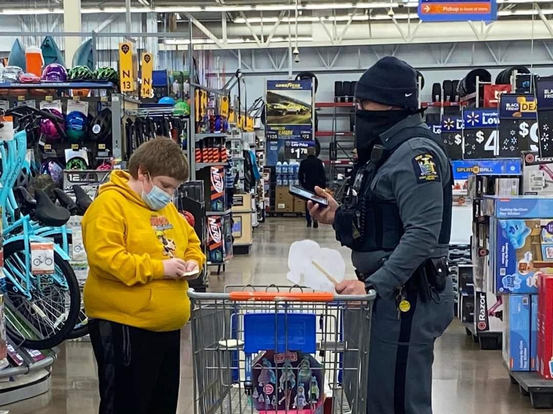 University Police Office Derek Wiebel helps young shopper Izaiah find presents for his family during Shop With a Hero