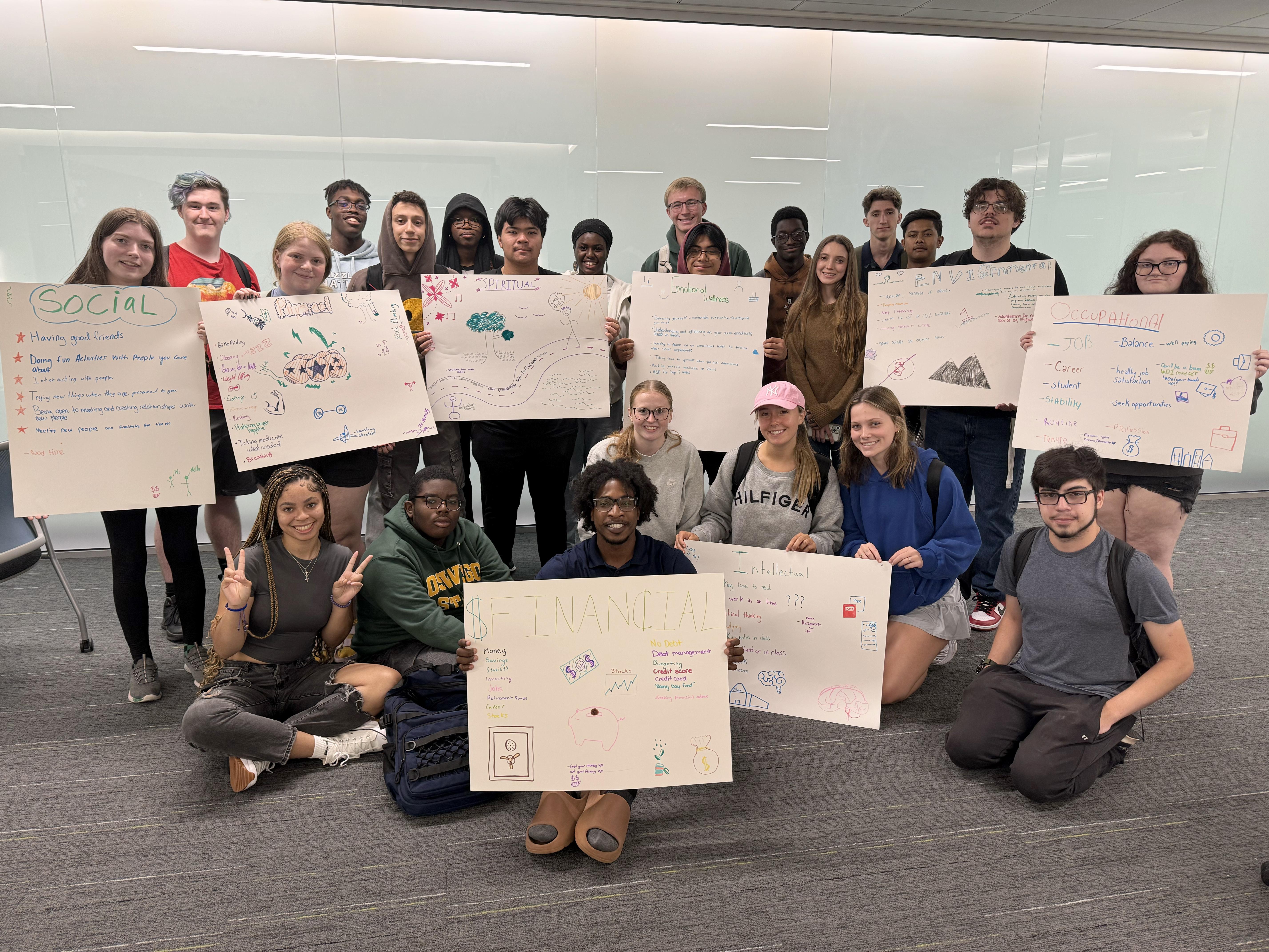 Students hold up signs related to the eight dimensions of wellness