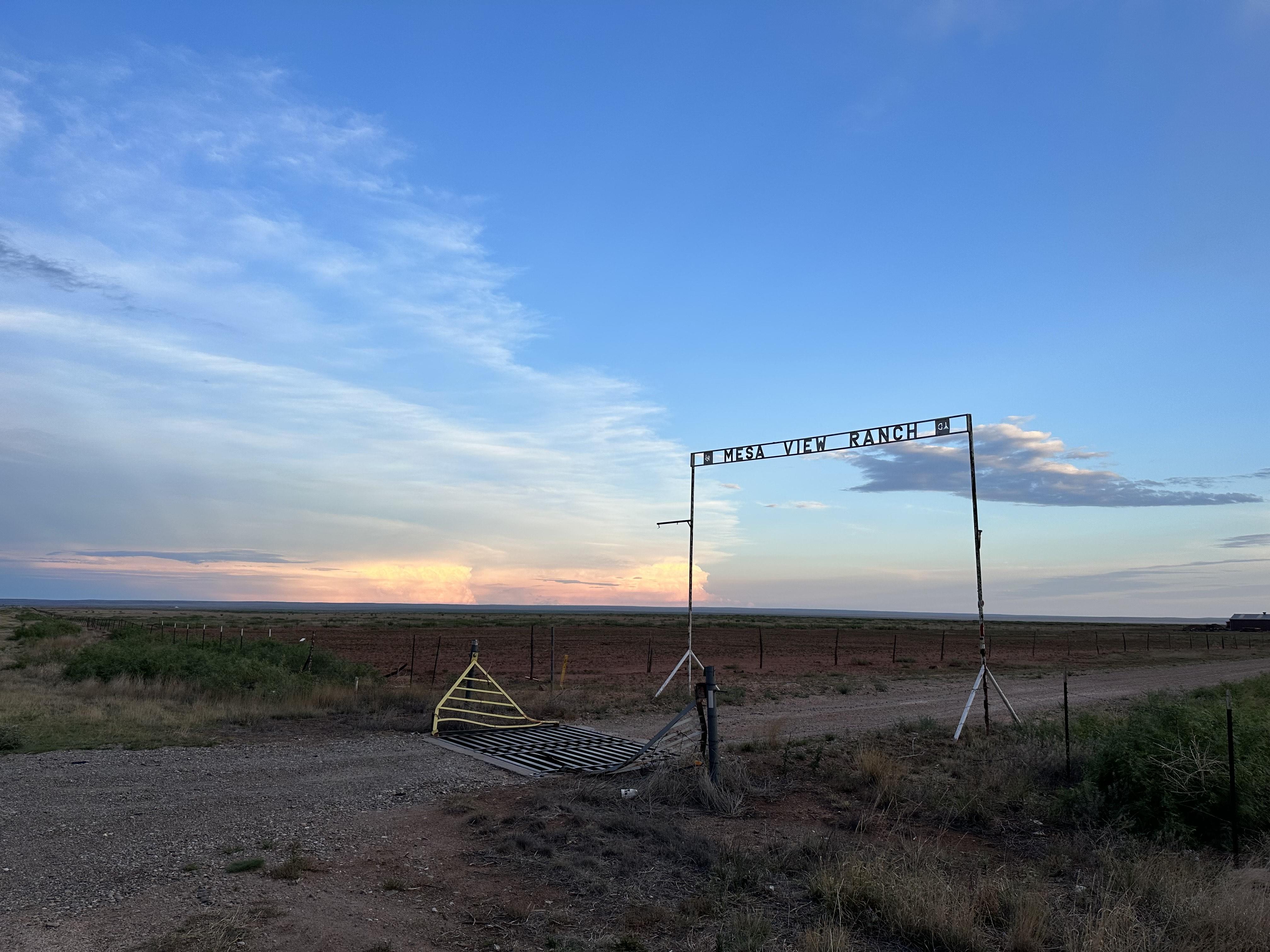 Metal sign reads "Mesa View Ranch" in front of the sunset.