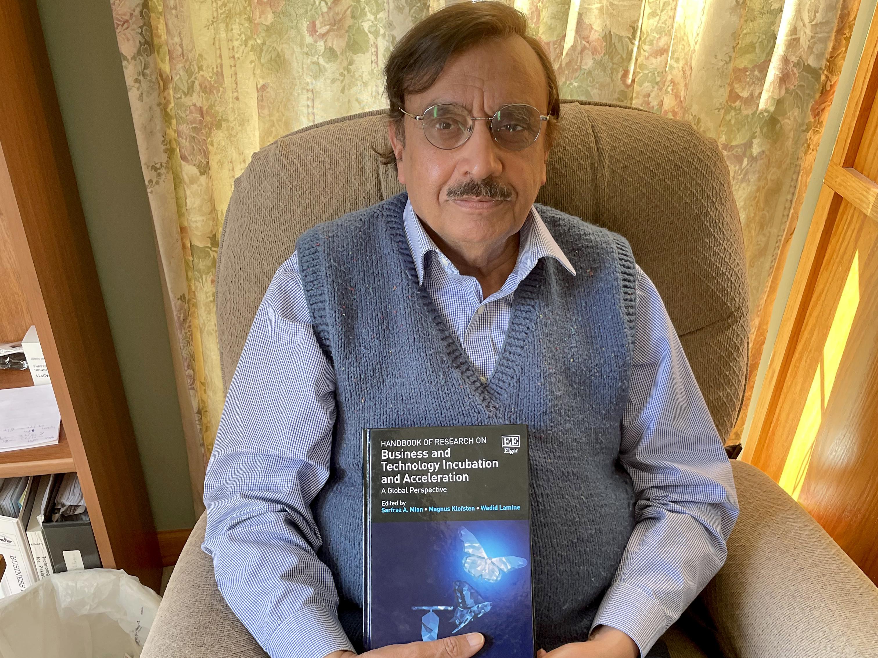 Sarfran Mian holds his most recent book, the first handbook for business incubation