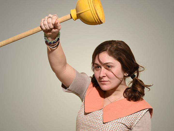 Michaela Buckley dancing while holding a plunger