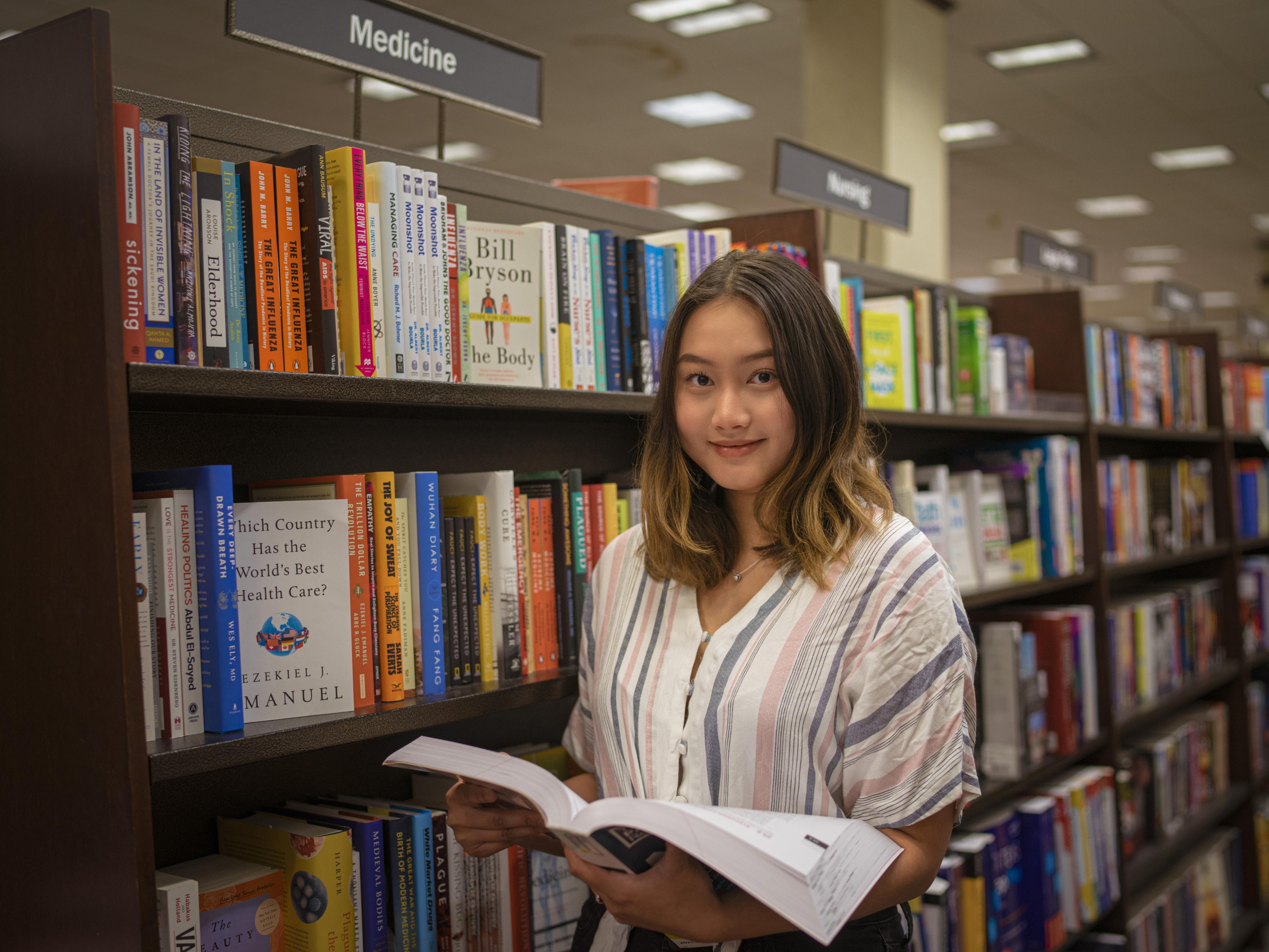 SUNY Oswego student Naw Ka Paw Paw, who earned a position in SUNY’s 2022 Premedical Opportunity Program, is shown among stacks of medical books
