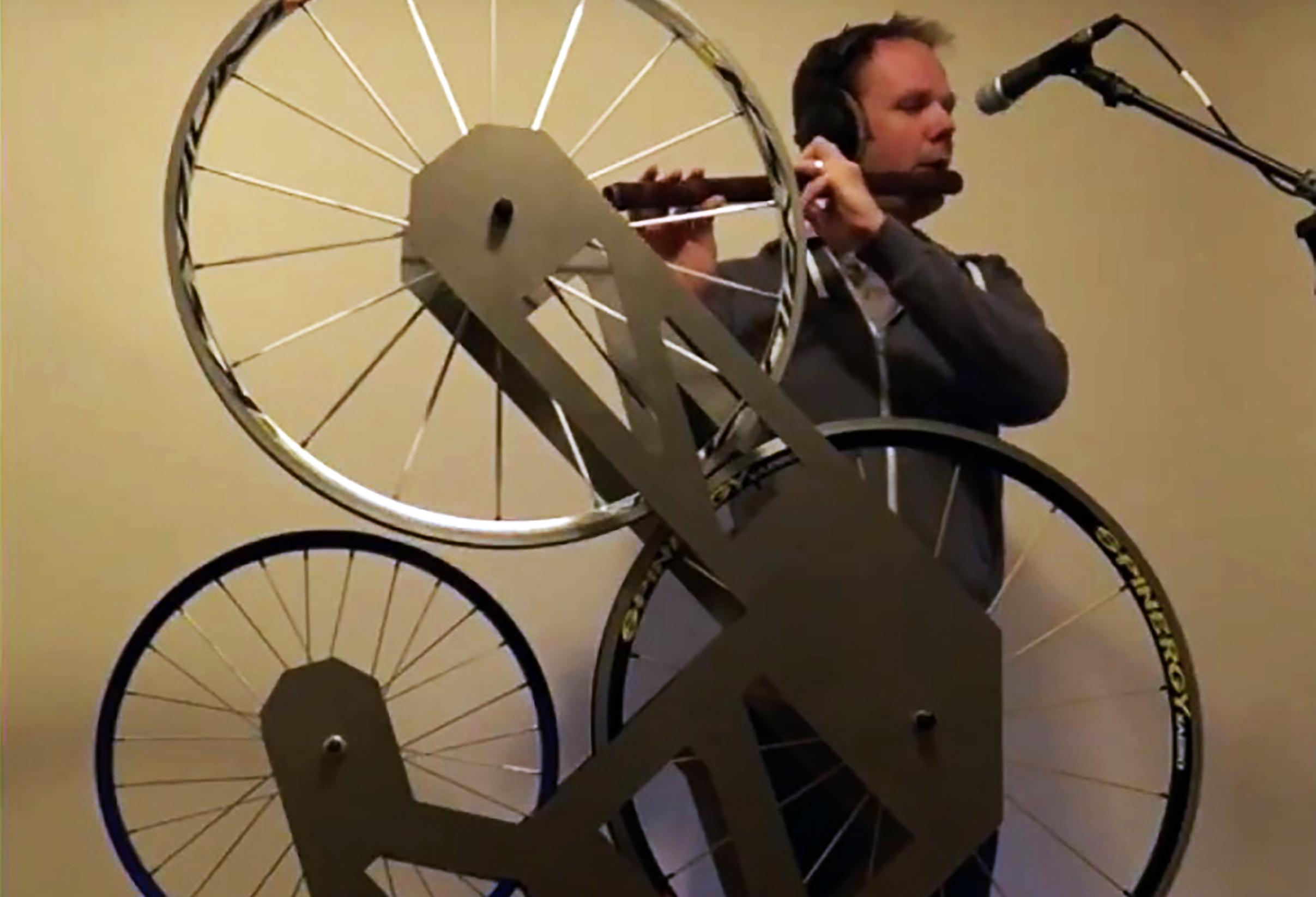 Music faculty member Paul Leary with instrument that combines flute with bicycle wheels