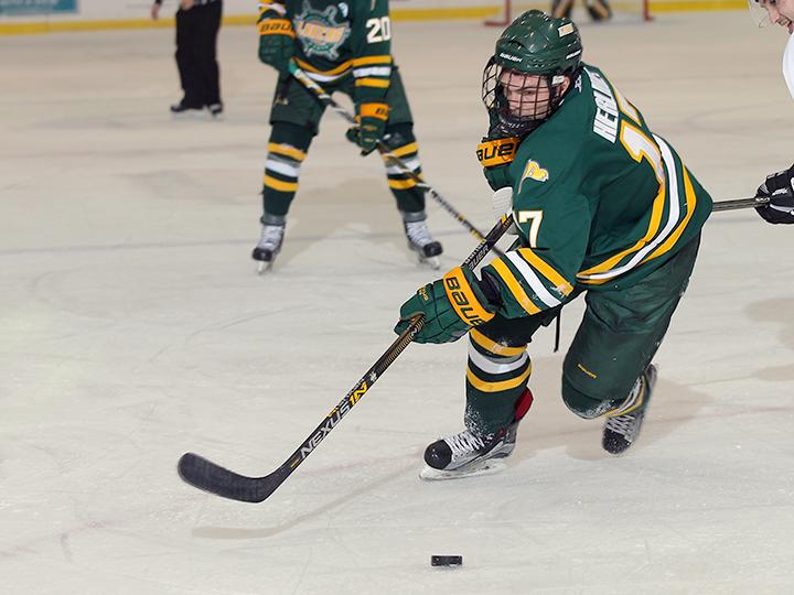 Men's hockey player Mitchell Herlihey skates with the puck