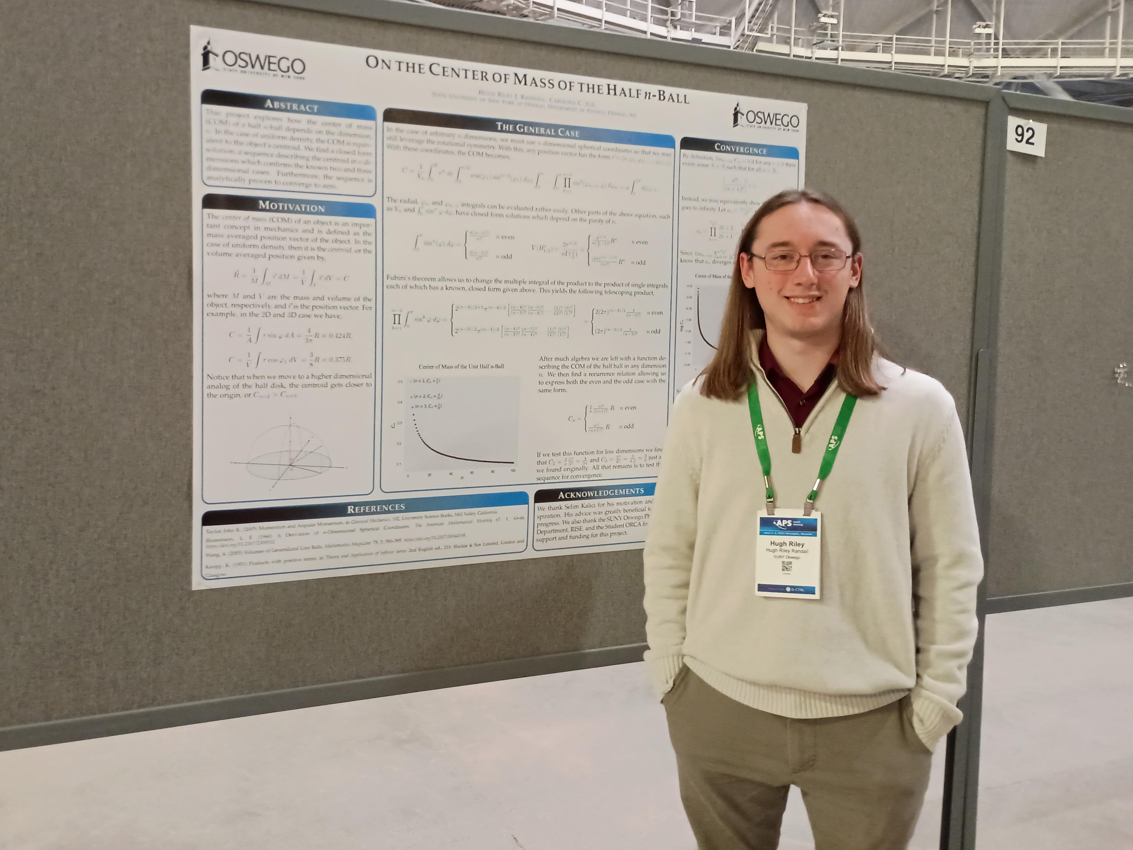 Hugh Riley Randall stands next to a poster presenting his research