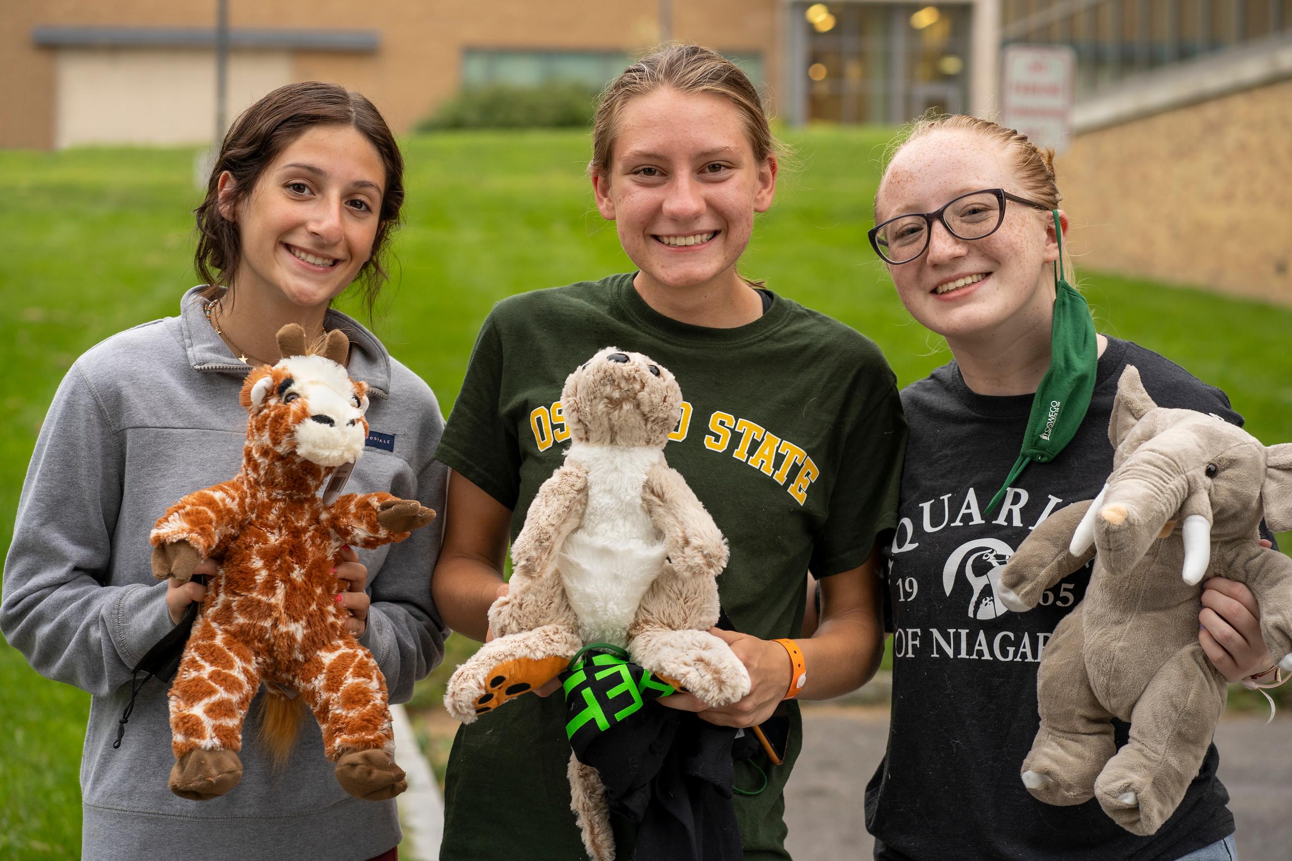 Three students hold up stuffed animals they assembled during 2021 Rec the Night new-student welcoming activity