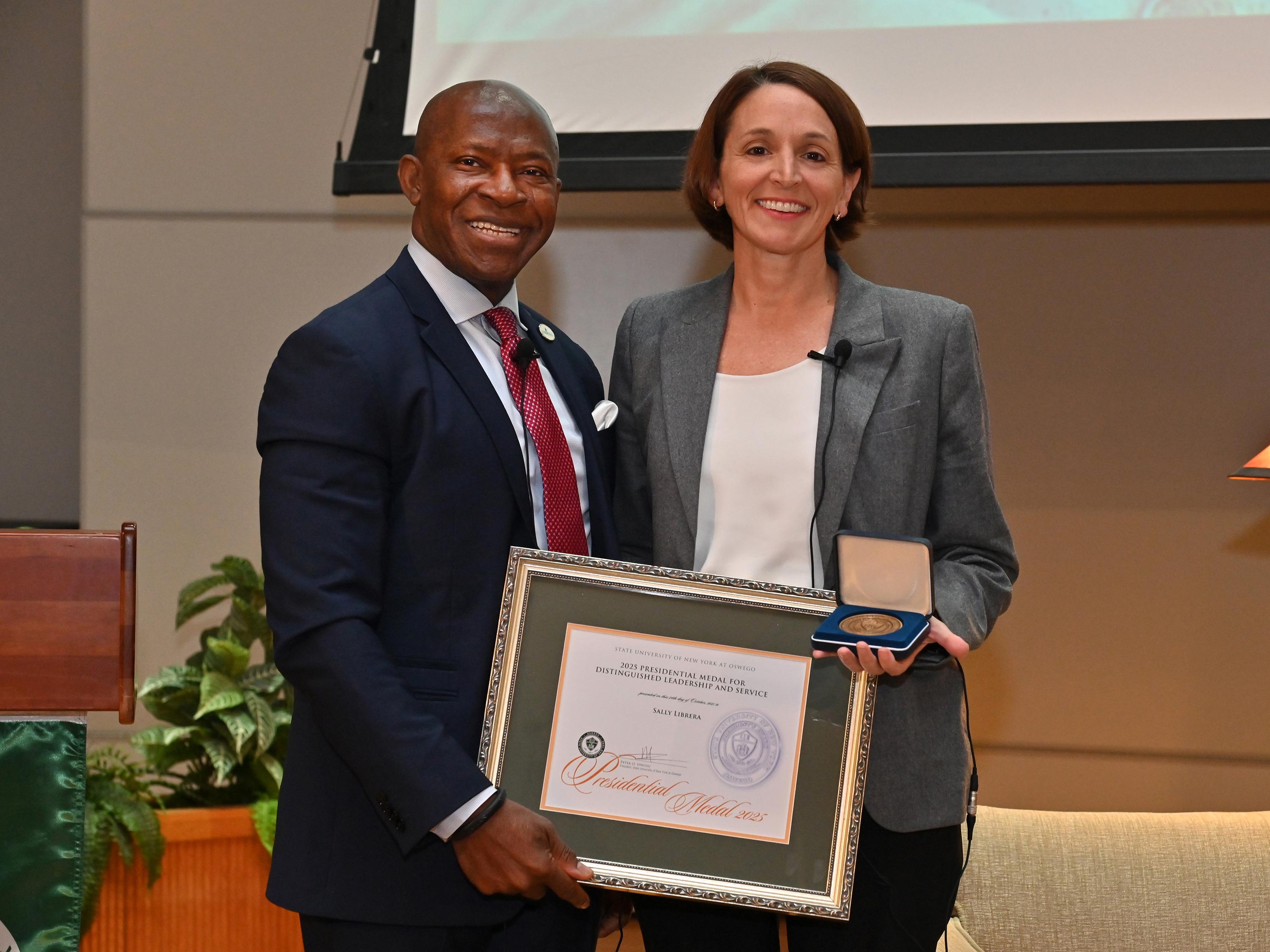 SUNY Oswego President Peter O. Nwosu presents Sally Librera, president of National Grid NY, with the Presidential Medal on Oct. 24, 2025, during the second annual Sheldon Lecture on Leadership and Service