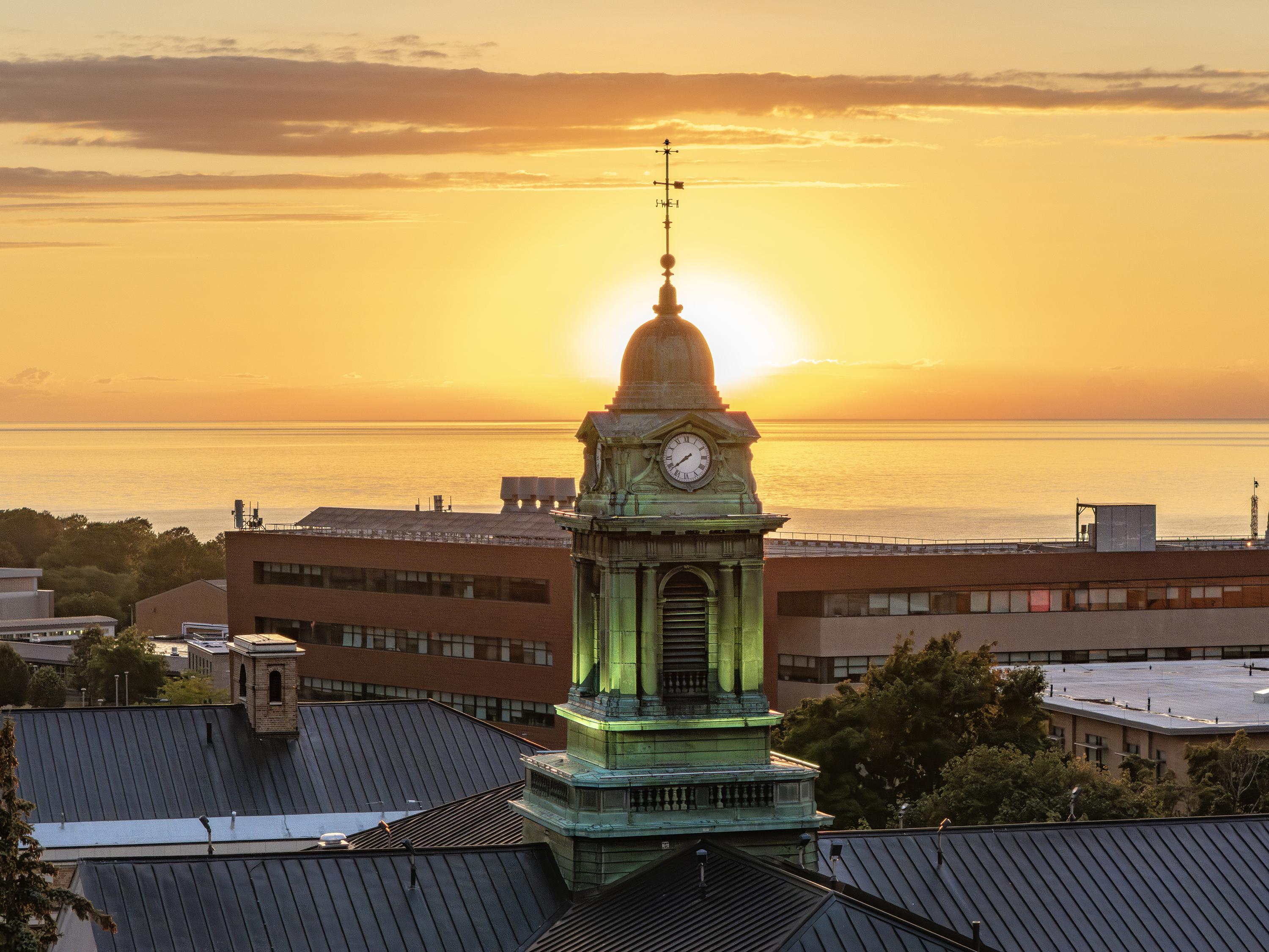 Scenic view of Sheldon Hall's cupola with lakeshore and sun in background