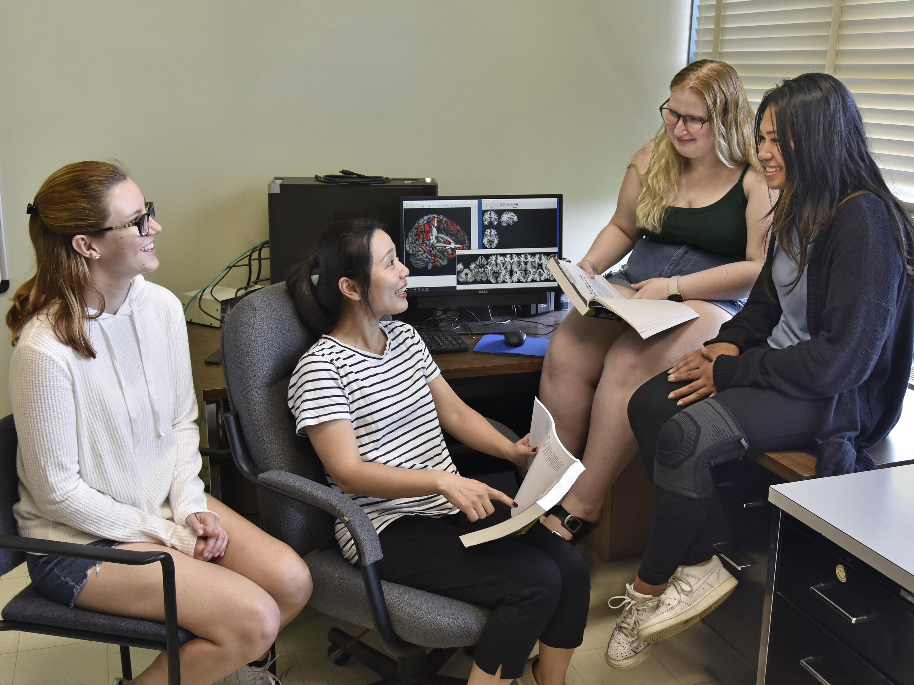 Psychology faculty member Sien Hu, seated second from left, speaks with student researchers