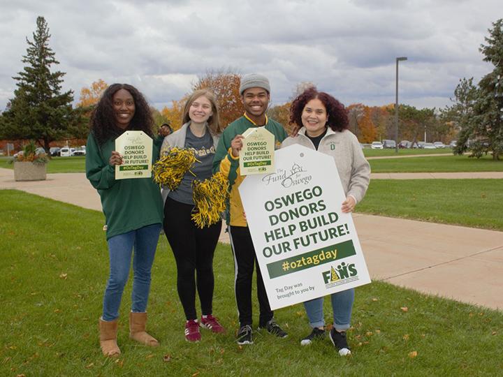 Students hold sign promoting tag day recognizing the importance of donors