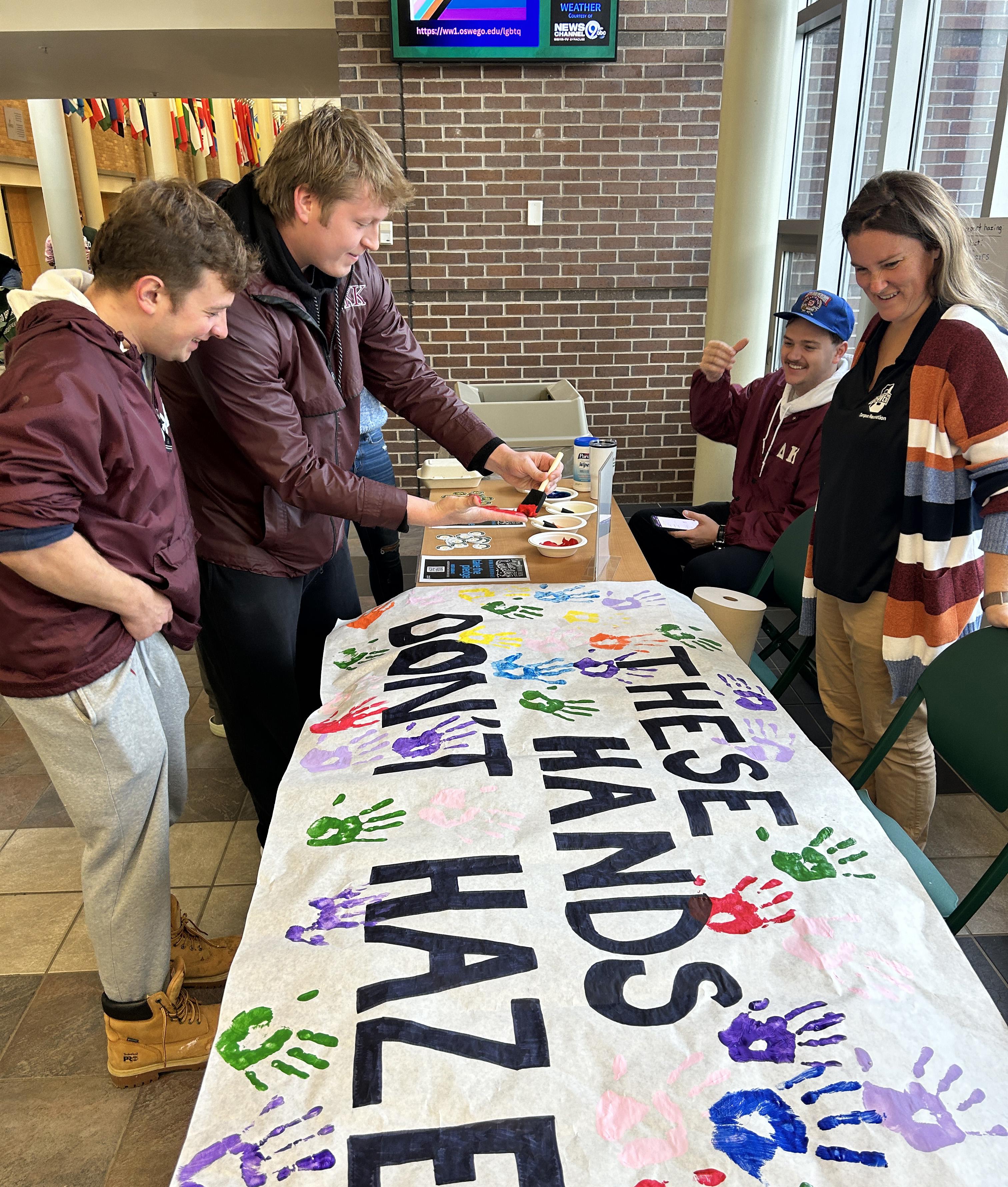 Students sign These Hands Don't Haze banner 