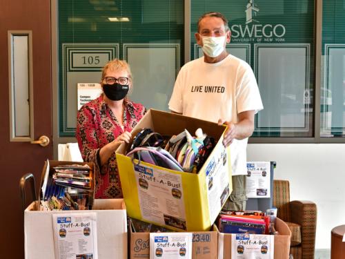SUNY Oswego State Employees Federated Appeal co-chair Cathy Johnston and Patrick Dewine, executive director of the United Way of Greater Oswego County, with some of the supplies from the 2021 Stuff a Bus drive