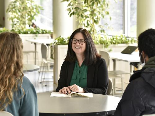 Christy Huynh talking with students Alyssa Frantz, a junior, and Aron Rezene, a senior