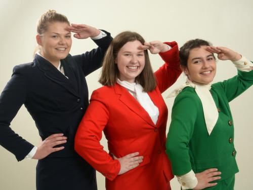 3 actresses dressed as stewardesses salute the camera