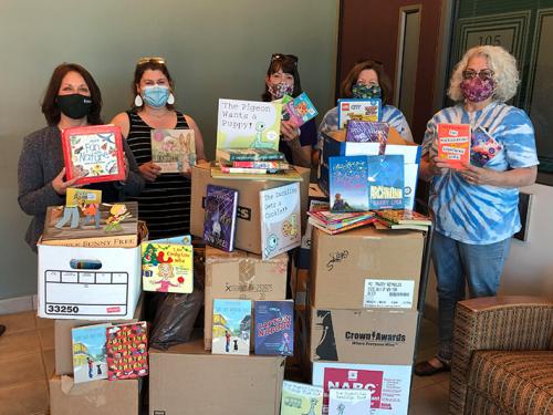 College participants and Oswego Bookmobile volunteers show off some of the hundreds of books donated to the local cause