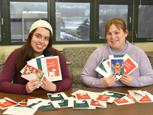 Sarah Gamarra and Jaclyn Schildkraut showing some of the donated holiday cards
