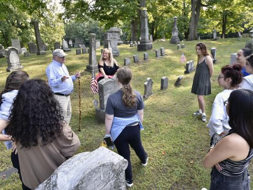 Oswego Town Historian (and 1966 SUNY Oswego alumnus) George DeMass speaks with theatre faculty member Jonel Langenfeld (center) and students from the college's storytelling class as they prepare for a family-friendly cemetery storytelling tour Oct. 29