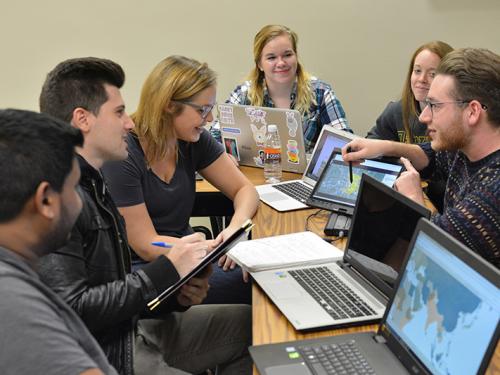 Students in front of computers discussing mapping project