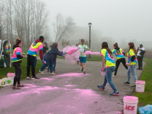 Volunteers throw powder on a color-run participant