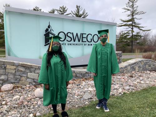 Taylor Clark and Daniel Garcia next to SUNY Oswego entrance sign