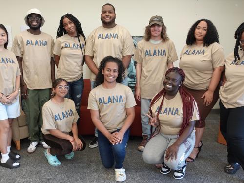 ALANA student leaders wearing tan ALANA conference shirts with blue and gold logo for the 36th annual conference themed Joyful Noise