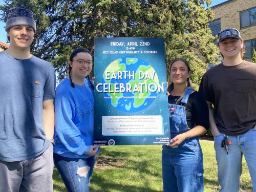 Four organizers of Earth Day activities hold up a poster