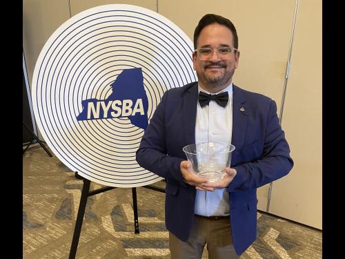 Francisco Suarez, associate professor in the communications department, poses with his trophy at the New York State Broadcasting Association awards ceremony.