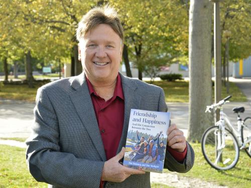 Tim Delaney with a book and fall foliage as a backdrop