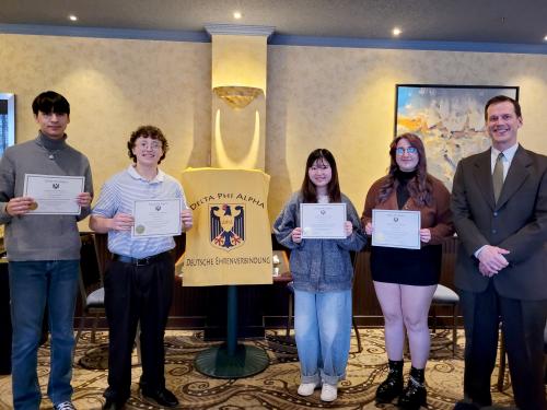 Students (from left) Clayton Andrews, Trey Woolwine, Misaki Naito and Kylie Thomas are welcomed to the SUNY Oswego chapter of Delta Phi Alpha, the National German Honor Society, by faculty member Patrick Schultz (at right).