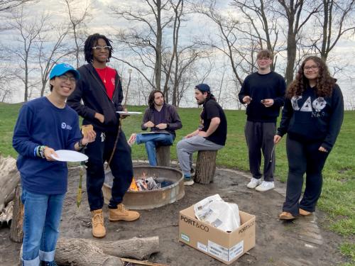 Great Lakes Institute interns and student volunteers with Shining Waters lakeshore cleanup pause during a post-pickup bonfire