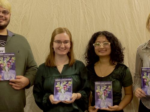 Students with Great Lake Review hold a previous edition of the magazine during a release party at the River's End Bookstore