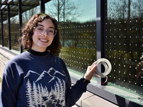 Senior zoology major Brooke Goodman shows off some of the window stickers at Rice Creek that serve as deterrents for birds