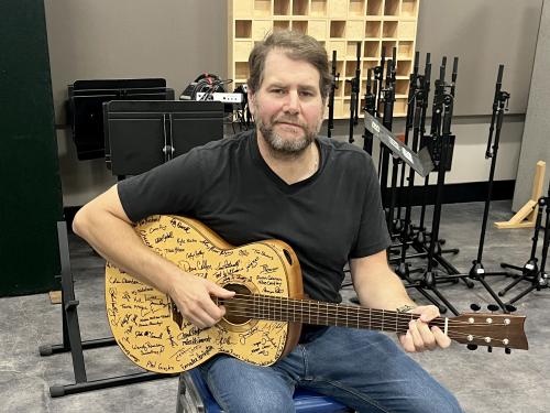 Tim Herron with the signature-covered guitar of the Oswego Guitar Project in a Tyler Hall studio
