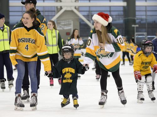 Laker women's hockey players skating with children