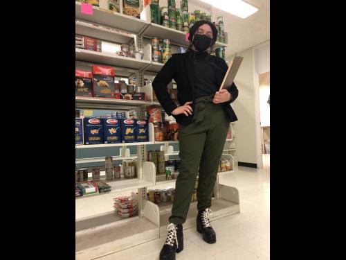 Senior Helena Buttons, SHOP Coordinator, standing in front of shelves with food at SHOP