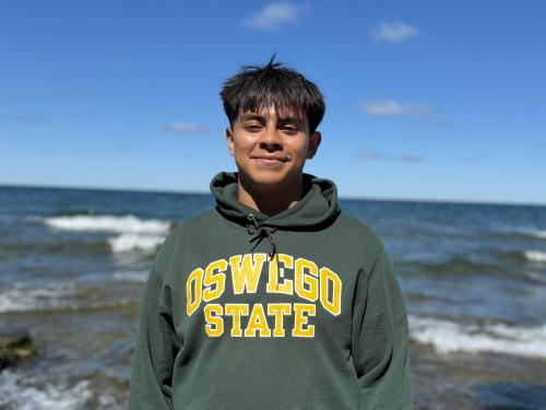 First-year SUNY Oswego student Axel Lopez smiling for a photo at Lake Ontario.