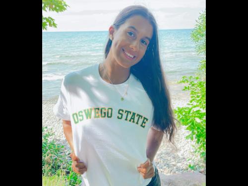 Jolie Santiago poses by Lake Ontario in a white Oswego State T-shirt