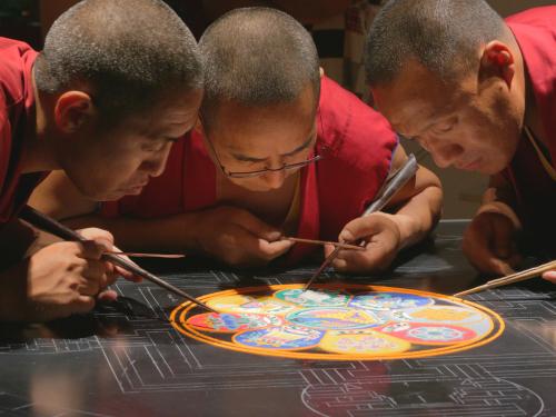 Monks work on creating mandala, beautiful sand art