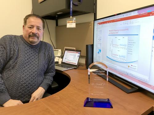 David Parisian with award and screen with data