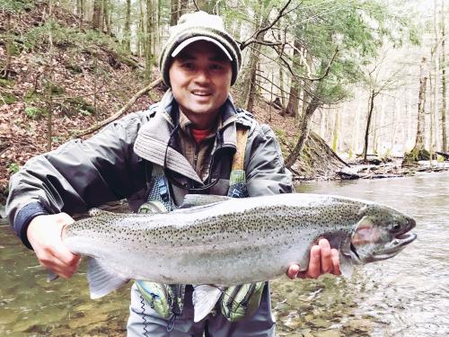 Michael Huynh holding a large fish while standing in a river