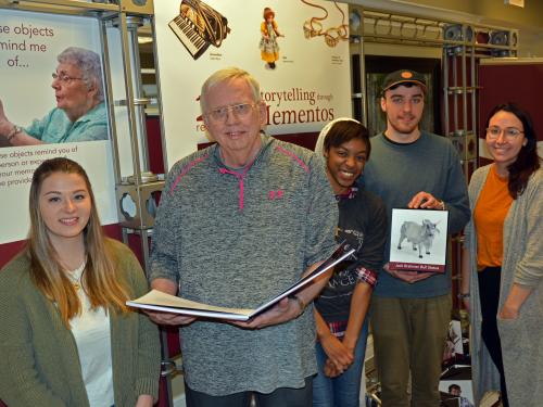 Students and a senior citizen with items from Recollections art exhibition