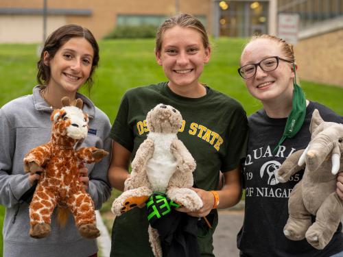 Three students hold up stuffed animals they assembled during 2021 Rec the Night new-student welcoming activity
