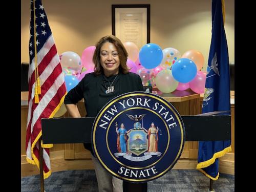 Maggie Rivera posing behind the senatorial seal during an awards ceremony