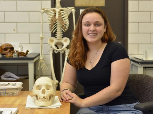 Hannah Kruse with a skull in a forensic lab