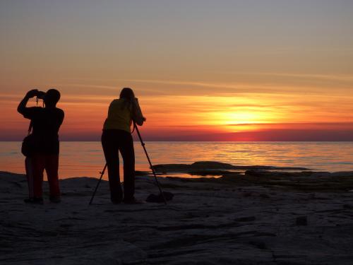 Two people take photographs on the shore of Lake Ontario
