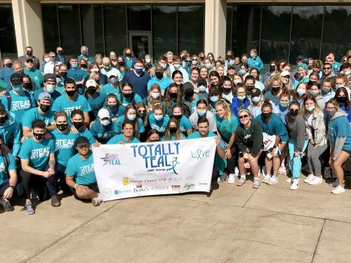 SUNY Oswego campus community members in a group wearing teal