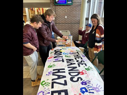 Students sign These Hands Don't Haze banner 
