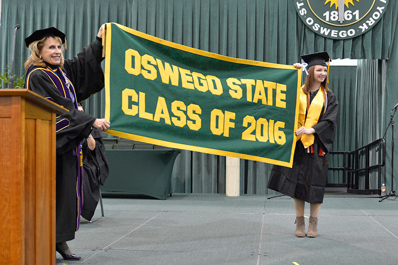 College President Deborah F. Stanley accepts the class banner from graduating senior Emily Pease